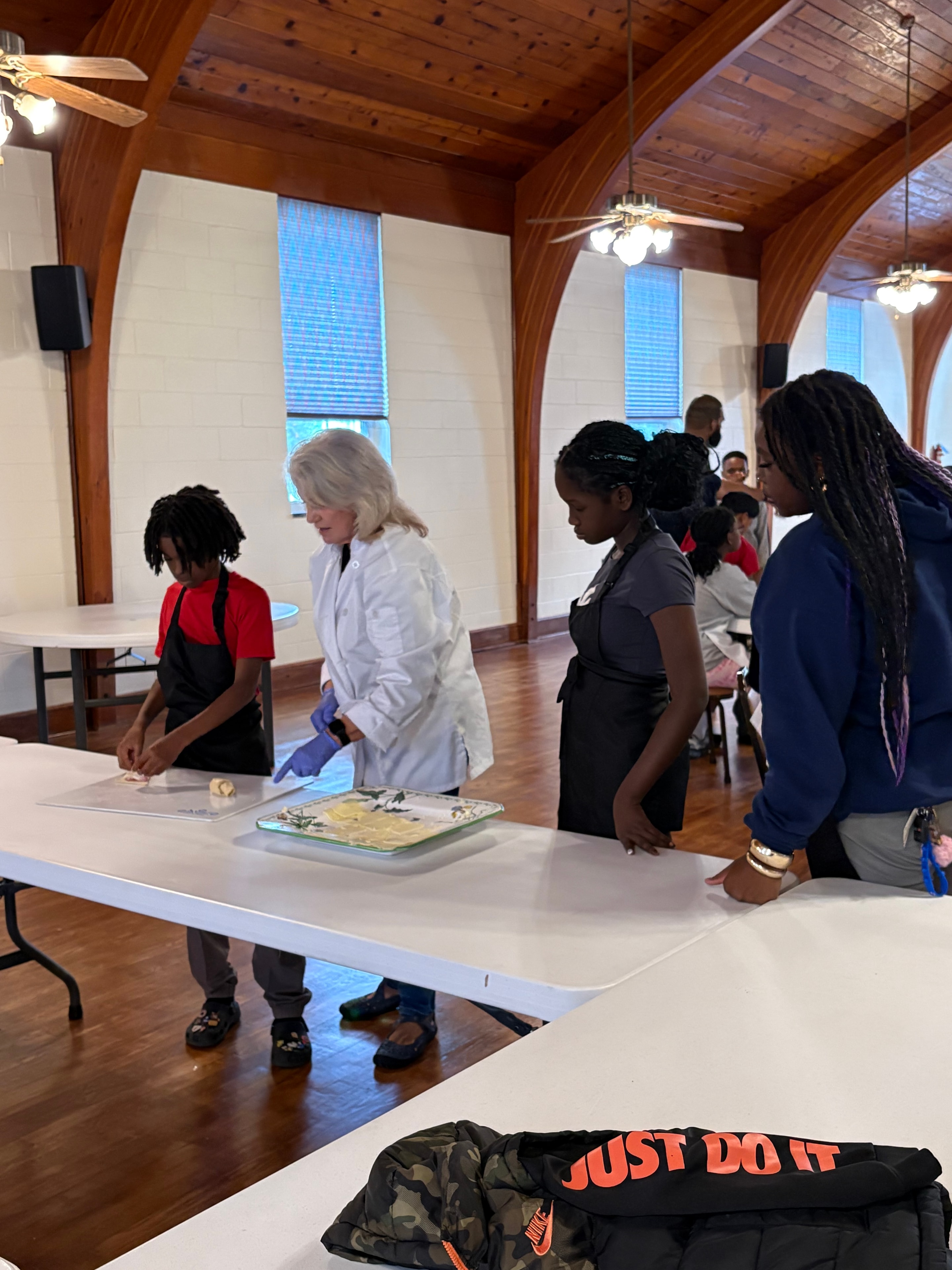 An instructor guiding children as they prepare food together at a Kids R Cookin' table